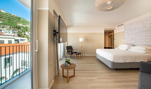 a bedroom with a bed and a balcony at Pestana Fisherman Village in Câmara de Lobos