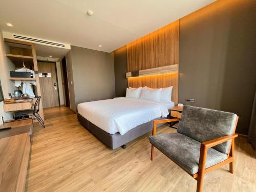 um quarto de hotel com uma cama e uma cadeira em The Teak Hotel em Mae Sot