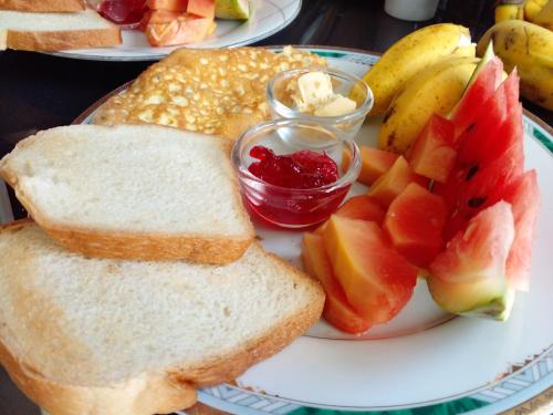 a plate of food with bread and fruit on a table at Vibe way (Hostel & Market farm) in Nuwara Eliya