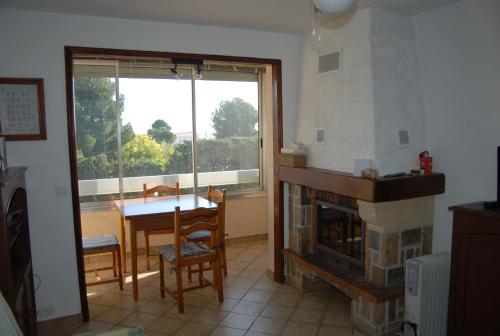 un salon avec une cheminée, une table et une fenêtre dans l'établissement appartement bord de mer, Esterel, à Agay