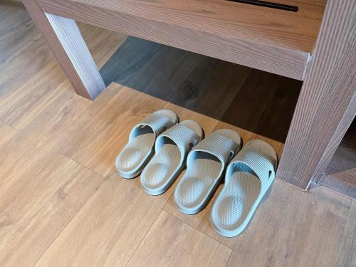 a row of pairs of shoes on the floor under a table at The Teak Hotel in Mae Sot