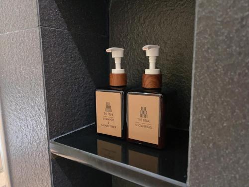 two bottles ofodorizers sitting on a shelf in a bathroom at The Teak Hotel in Mae Sot