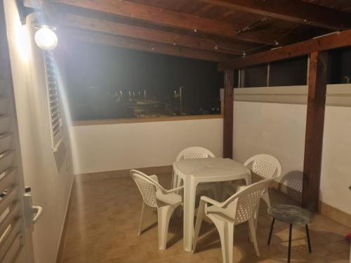 een witte tafel en stoelen in een kamer met een raam bij Casa vacanze appartamento Policoro ( Matera ) vicino al mare in Policoro