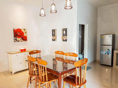 a dining room with a table and chairs and a refrigerator at Rosetta Homestay in Batu