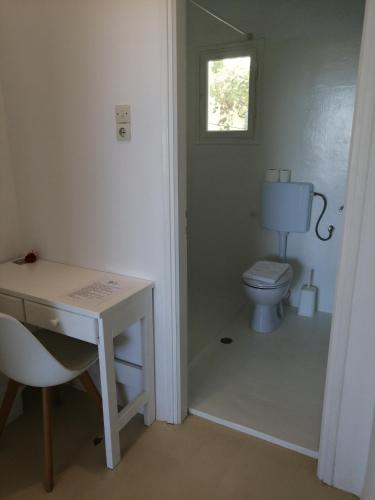 a bathroom with a toilet and a desk and a window at Aliki Panorama Rooms -breakfast included- in Aliki