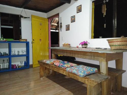 a room with a table and benches and a yellow door at Bangalô Boa Ventura in Lumiar
