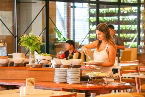 a woman standing in a restaurant preparing food at Crystal Jade Hotel in Rayong