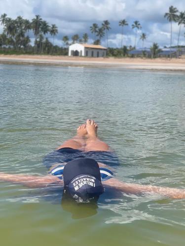 a man laying in the water in the ocean at Chalé Palhano Beach in São Miguel dos Milagres