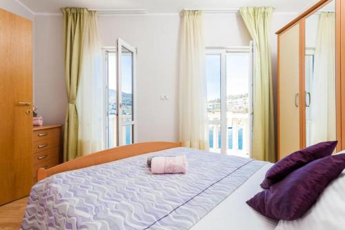 Un dormitorio con una cama con almohadas moradas y una ventana en Apartments Dea Caeli, en Vela Luka