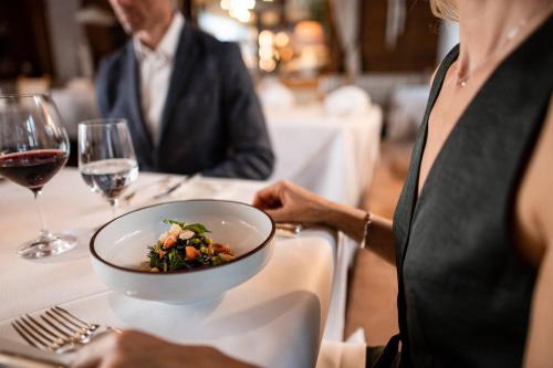 a woman sitting at a table with a bowl of food at Romantik Hotel & Restaurant Stafler in Vipiteno