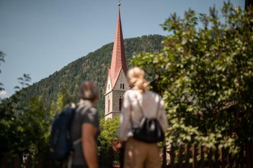 two people are standing in front of a church at Romantik Hotel & Restaurant Stafler in Vipiteno
