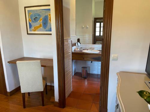 a bathroom with a sink and a table with a chair at Rectoral de Cines in Oza dos Ríos