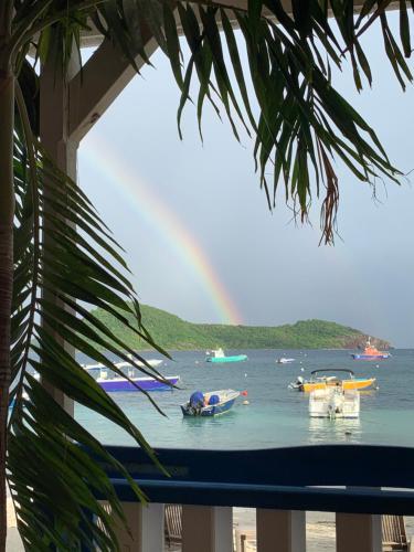 a rainbow over a beach with boats in the water at Villa GRENADINE Vue panoramique, les pieds dans l'eau in Terre-de-Haut