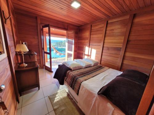 a bedroom with a bed with wooden walls and a window at Hotel Fazenda Boutique Terra do Gelo in Bom Jardim da Serra