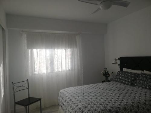 - une chambre avec un lit, un ventilateur de plafond et une fenêtre dans l'établissement Apartamento la estrella, los cristianos, à Los Cristianos