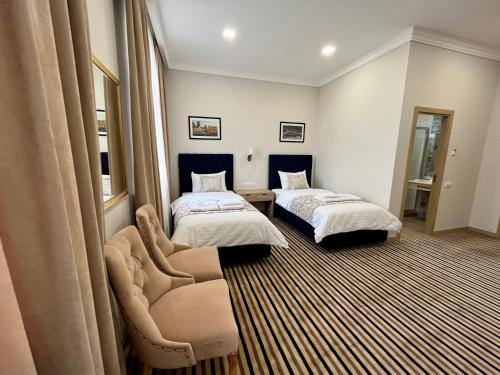 ein Hotelzimmer mit 2 Betten und einem Stuhl in der Unterkunft Bristol Hotel Tashkent in Taschkent