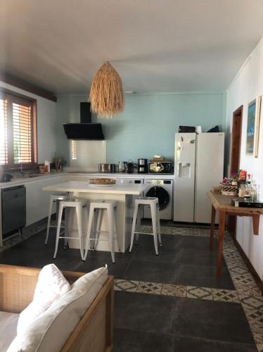 a kitchen with a white table and a white refrigerator at Villa GRENADINE Vue panoramique, les pieds dans l'eau in Terre-de-Haut