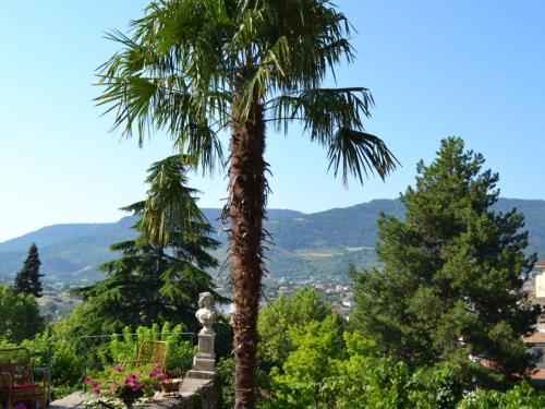 two palm trees in a garden with mountains in the background at La Maison Jaffran, suite en ville in Privas