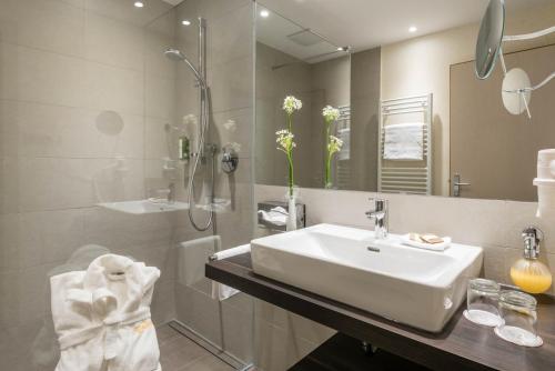 a bathroom with a sink and a shower and a mirror at Romantik Hotel & Restaurant Stafler in Vipiteno