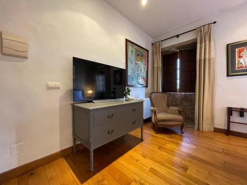 a room with a dresser with a television and a chair at Rectoral de Cines in Oza dos Ríos