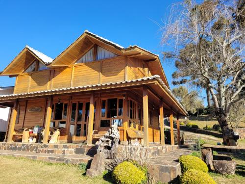 uma grande casa de madeira com uma árvore em frente em Hotel Fazenda Boutique Terra do Gelo em Bom Jardim da Serra