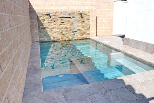 a swimming pool with a bench and a brick wall at Bungalow La Roa II in Conil de la Frontera