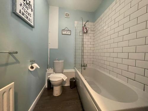 a bathroom with a toilet and a tub and a sink at The Old Office - 1 Bed Studio in Swansea