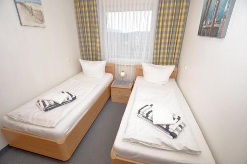 2 aparte bedden in een kamer met een raam bij Appartement-254 in Westerland