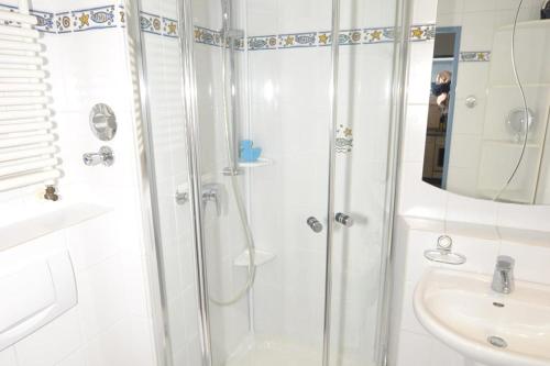 een witte badkamer met een douche en een wastafel bij Appartement-254 in Westerland