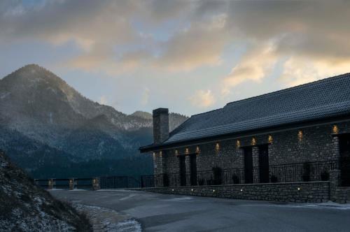 a stone building with a mountain in the background at Δωμάτια με θέα in Méga Khoríon