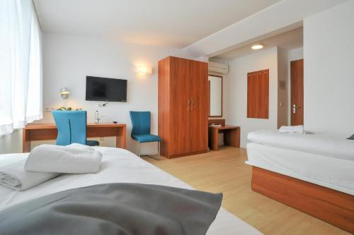 a bedroom with two beds and a desk and a tv at Gästehaus abz Stuttgart in Stuttgart