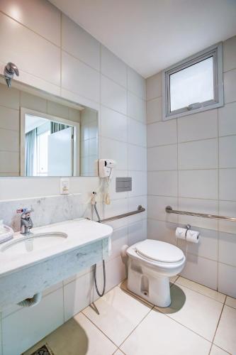 a bathroom with a toilet and a sink and a mirror at Transamerica Fit Vitória Reta da Penha in Vitória