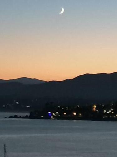 a sunset with the moon over a city and a body of water at Depto Ambiente Privado con Vista al Mar in Concón