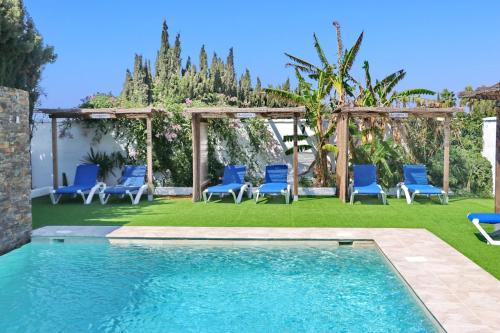 a swimming pool with blue chairs and a gazebo at Chalet La Roa III in Conil de la Frontera