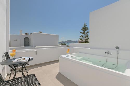 a bathroom with a tub and a table and a chair at Naxos Blue Sky in Naxos Chora