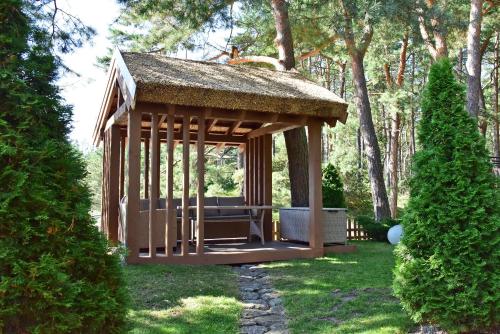 a gazebo with a thatched roof in a yard at Vila Deva in Neringa