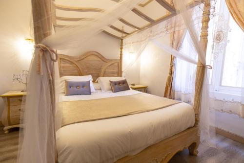 ein Schlafzimmer mit einem Himmelbett und einem Fenster in der Unterkunft Chambre a Baldaquin Maison de L'Église Du couvent in Narbonne