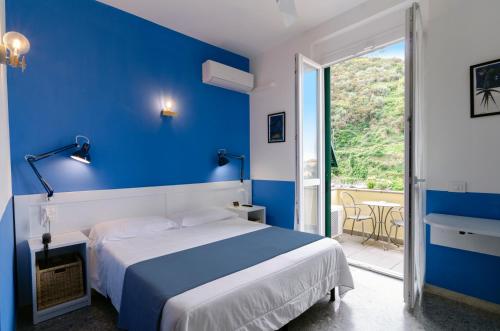 a blue bedroom with a bed and a balcony at Hotel Villa Argentina in Riomaggiore