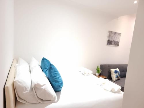 - un canapé blanc avec des oreillers bleus dans le salon dans l'établissement F1-Basement Studio Fits 3 Near Paddington, à Londres
