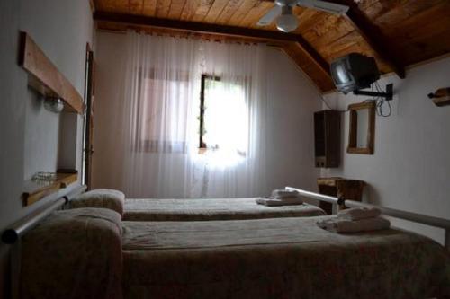 1 dormitorio con 2 camas y ventana en Hotel Alihuen en Sierra de la Ventana