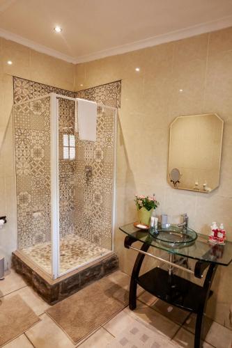 a bathroom with a shower with a sink and a mirror at Town and Country Mpumalanga in Middelburg