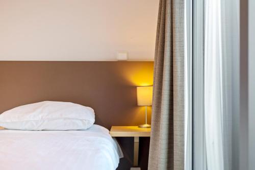 um quarto com uma cama, uma mesa e uma janela em Belcasa Suitehotel em Middelkerke