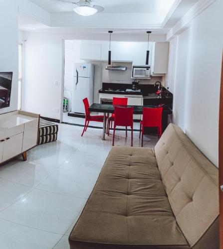 a living room with a couch and a table and red chairs at Apartamento reformado na melhor localização a 100 metros da praia,comodidade inclui ,garagem,internet,elevadores duas cadeiras de praia ,cooler,roupas de cama e banho in Guarapari
