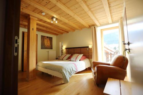 um quarto com uma cama, uma cadeira e uma janela em Le Valombré em Saint-Pierre-de-Chartreuse