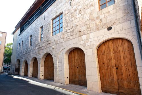 a brick building with four brown wooden garage doors at Chambre a Baldaquin Maison de L'Église Du couvent in Narbonne