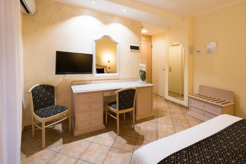 a bedroom with a desk with a mirror and a bed at Sant Alphio Garden Hotel & SPA in Giardini Naxos