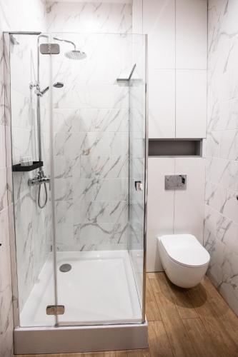 a white bathroom with a shower and a toilet at Kulikovskiy hotel in Kharkiv