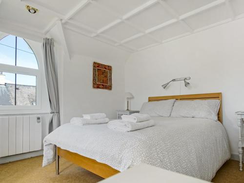 a bedroom with a bed with white sheets and a window at Pass the Keys South Lodge Coastal Cottage in Dyffryn