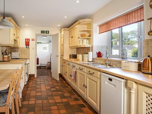 Il comprend une cuisine avec des placards en bois et du carrelage. dans l'établissement Pass the Keys South Lodge Coastal Cottage, à Dyffryn