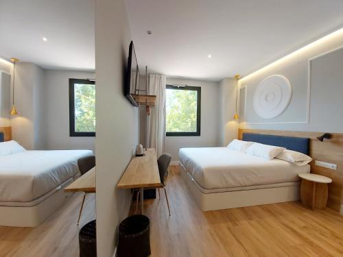 a hotel room with two beds and a table at Habital Suites in Jaca